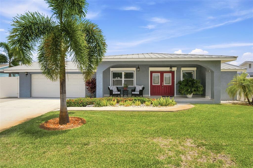 A single-story gray house with a metal roof, red double front doors, and a palm tree — 485 FLAMINGO DRIVE, APOLLO BEACH, FL
