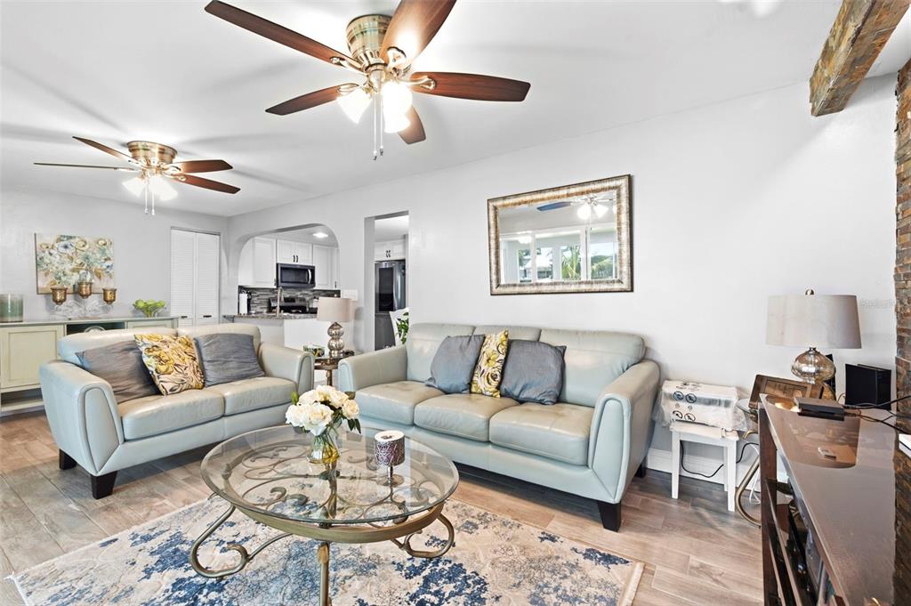 A living room features two light-colored leather sofas, a glass coffee table, and ceiling fans — 485 FLAMINGO DRIVE, APOLLO BEACH, FL