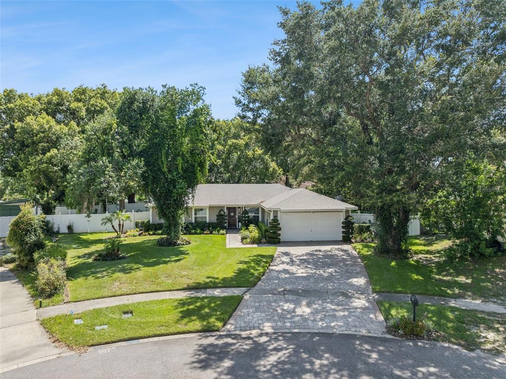 A single-story house with a paved driveway and large trees sits on a grassy lot — 1708 CREOLE COURT, ORLANDO, FL
