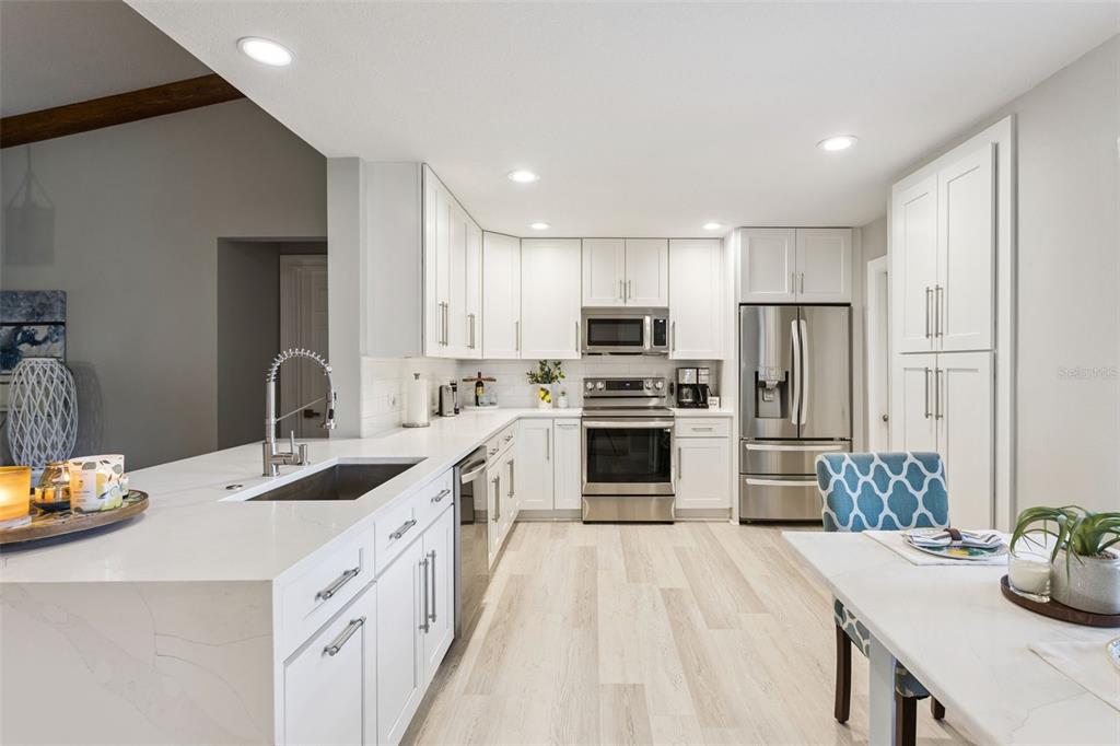 A modern kitchen features white cabinetry, stainless steel appliances, and a large quartz-topped island — 1708 CREOLE COURT, ORLANDO, FL