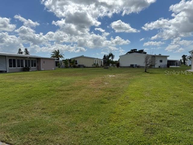 A grassy vacant lot is situated between several manufactured homes under a cloudy blue sky — 675 ALVARADO, NORTH PORT, FL