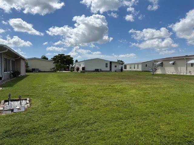 A grassy vacant lot is situated between several manufactured homes under a cloudy blue sky — 675 ALVARADO, NORTH PORT, FL