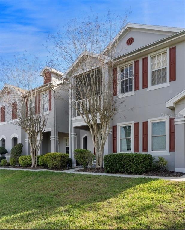 A multi-story residential building features gray stucco siding, red shutters, and a screened balcony — 10409 CRIMSON PARK LANE UNIT 105, TAMPA, FL