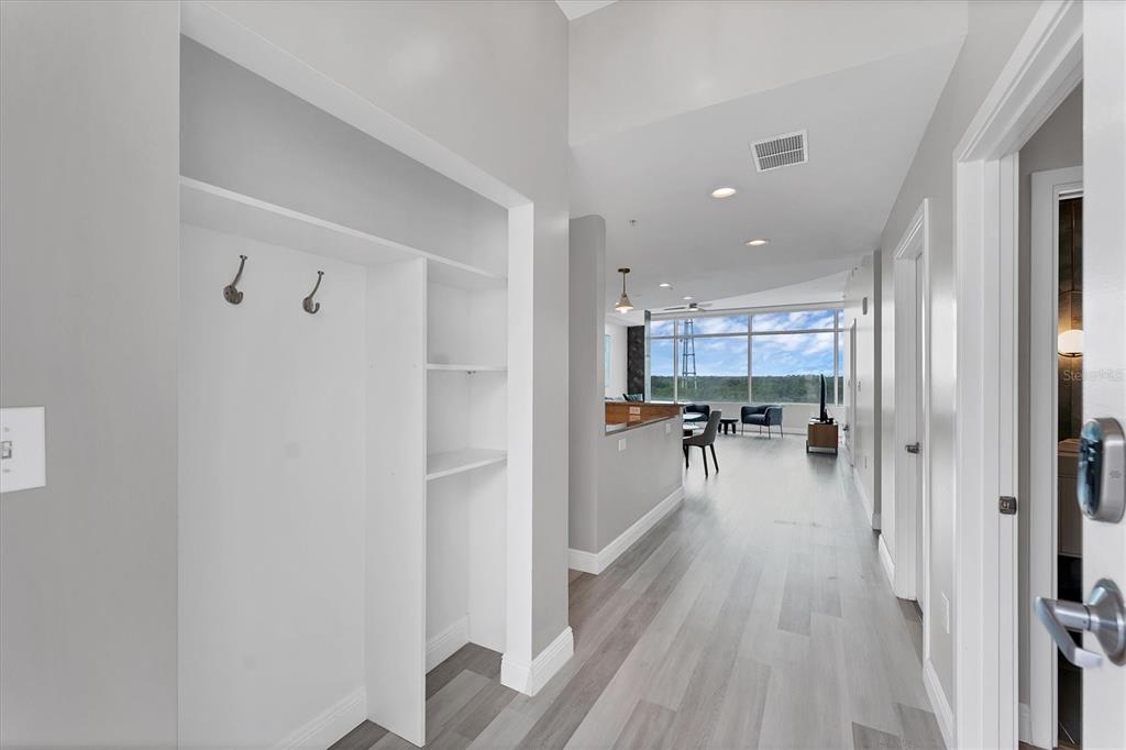 A hallway with light wood floors leads to an open living area with floor-to-ceiling windows — 525 E JACKSON STREET UNIT 705, ORLANDO, FL