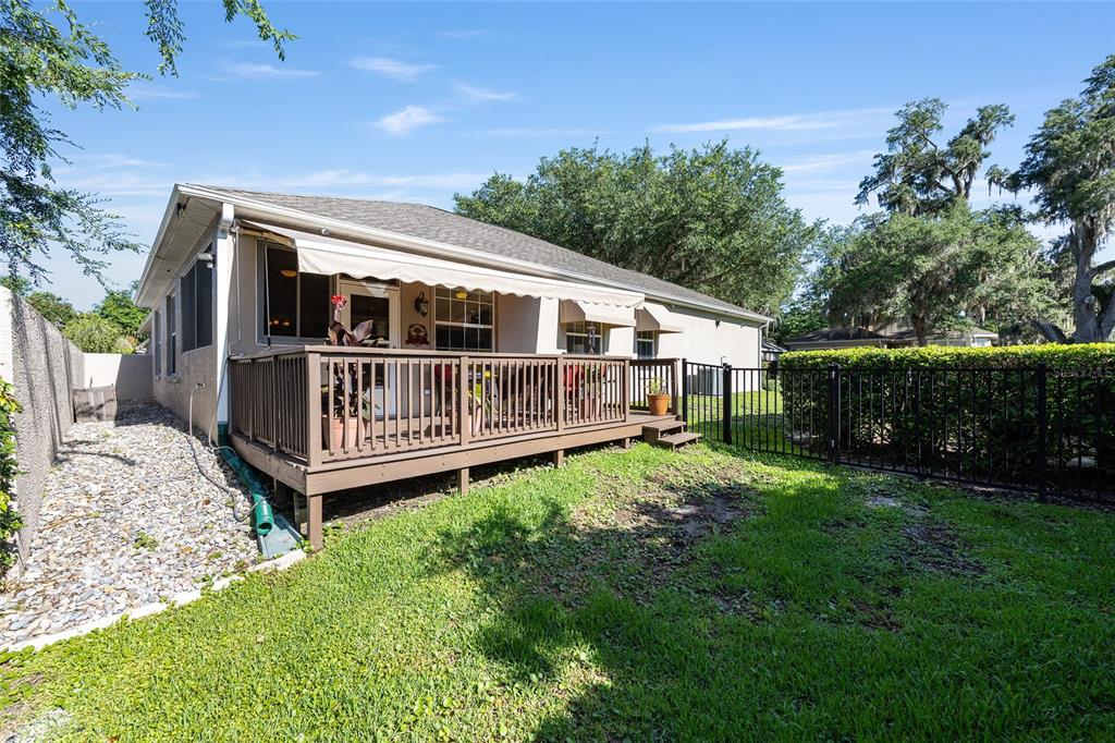 A backyard view of a house featuring a wooden deck with an attached retractable awning — 3304 SW 38TH STREET, OCALA, FL