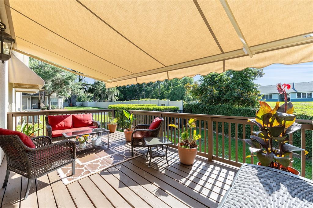 A wooden deck features patio furniture and a retractable awning overlooking a grassy backyard — 3304 SW 38TH STREET, OCALA, FL