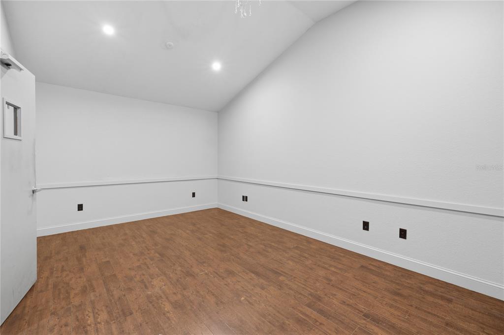 An empty room features white walls with chair rail molding, recessed lighting, and wood flooring — 2250 N VOLUSIA AVENUE, ORANGE CITY, FL