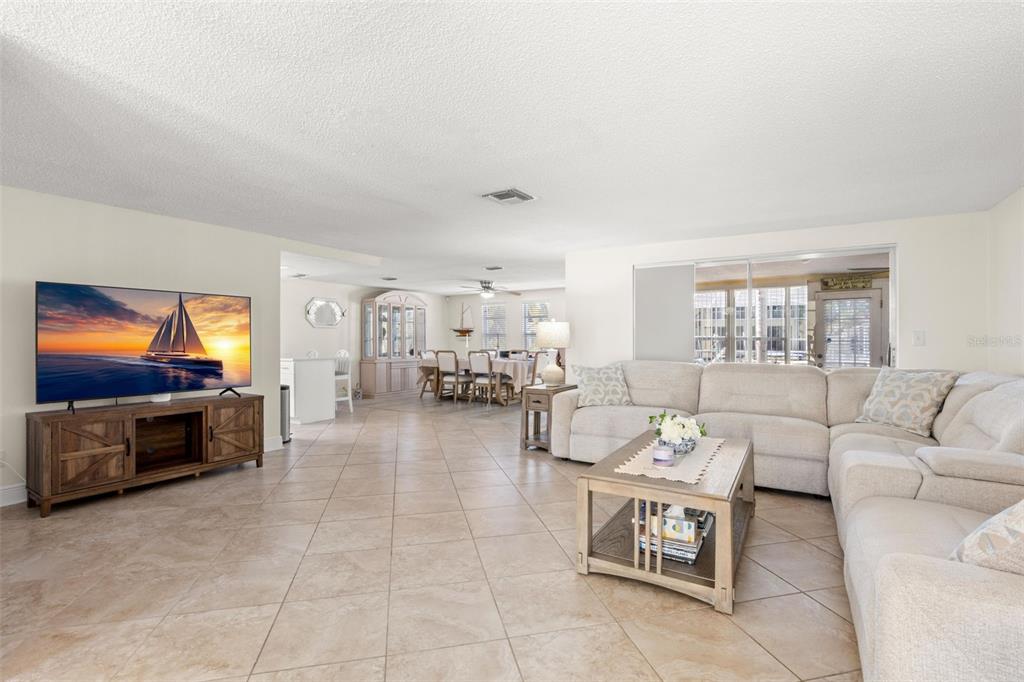A spacious living room features light tile floors, a sectional sofa, and a television console — 7418 ISLANDER LANE, HUDSON, FL