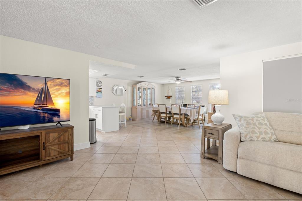 A living room with tile floors flows into a dining area and kitchen — 7418 ISLANDER LANE, HUDSON, FL