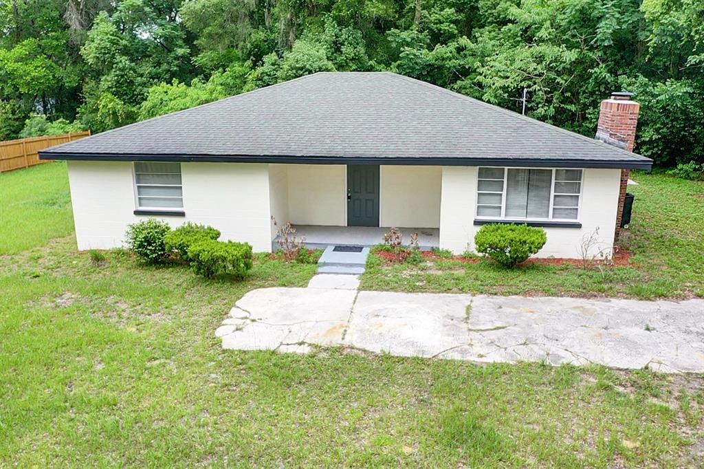 A single-story house with a white brick exterior, dark roof, and a front concrete walkway — 1251 NW 23RD AVENUE, OCALA, FL