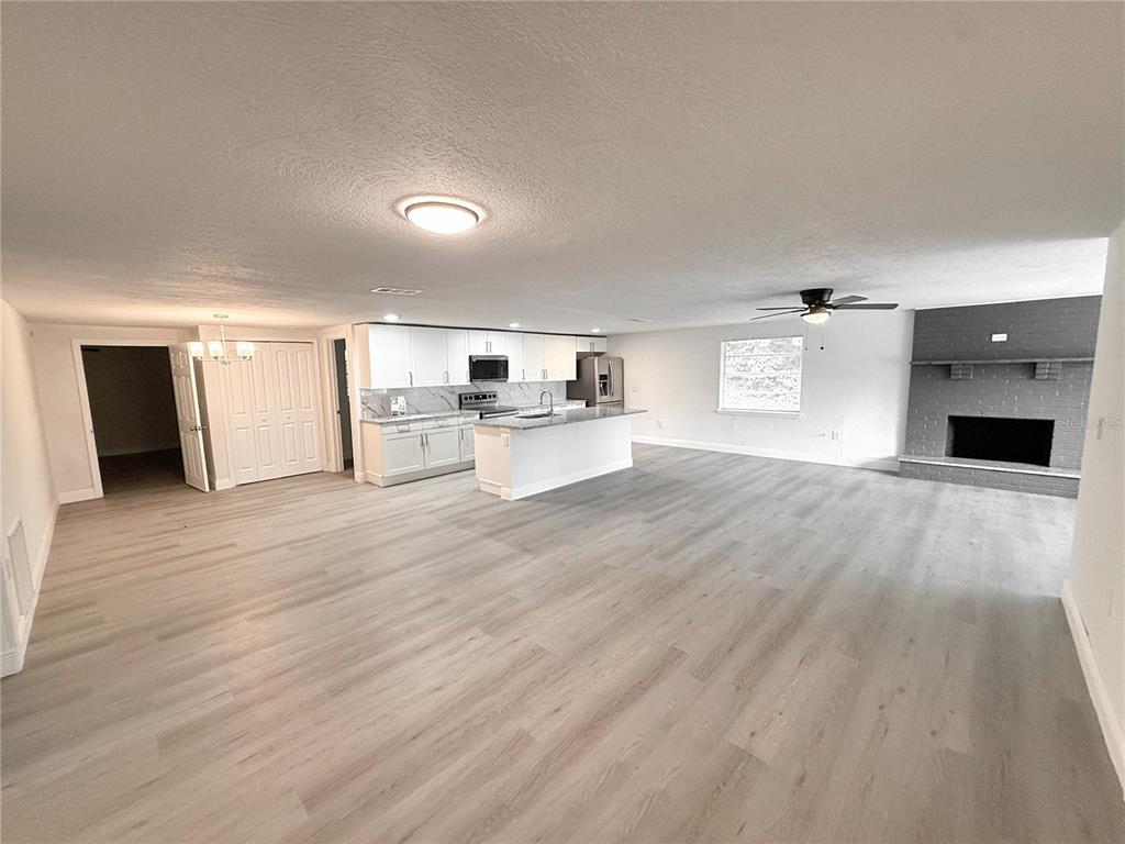 An open-concept living area features a kitchen with white cabinets, an island, and a fireplace — 1251 NW 23RD AVENUE, OCALA, FL