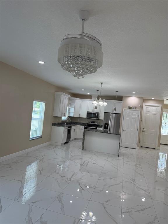 A kitchen with white cabinets, dark countertops, and white marble-look tile flooring — 1923 W SKAGWAY AVENUE, TAMPA, FL