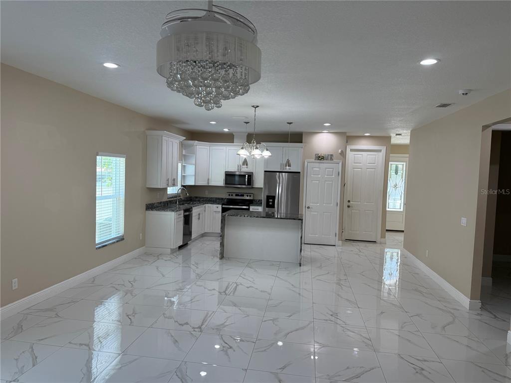 A dining area with a wooden table and chairs adjacent to a modern white kitchen — 1923 W SKAGWAY AVENUE, TAMPA, FL