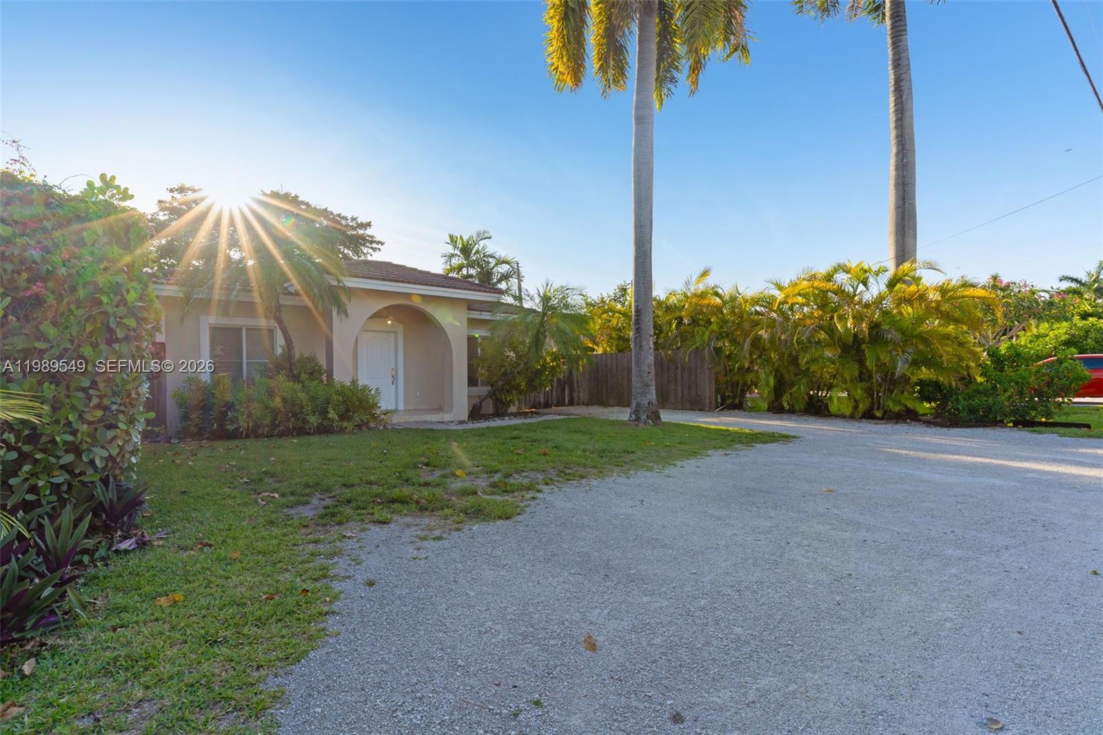 A single-story house with a white door and arched entryway sits behind a gravel driveway — 7048 SW 83rd Ct, Miami FL 33143, MIAMI, FL