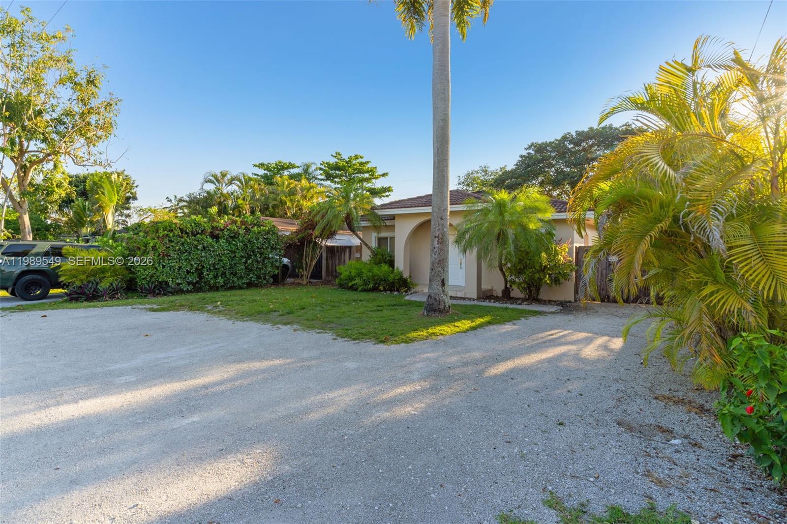 A single-story house with a gravel driveway, palm trees, and lush landscaping — 7048 SW 83rd Ct, Miami FL 33143, MIAMI, FL