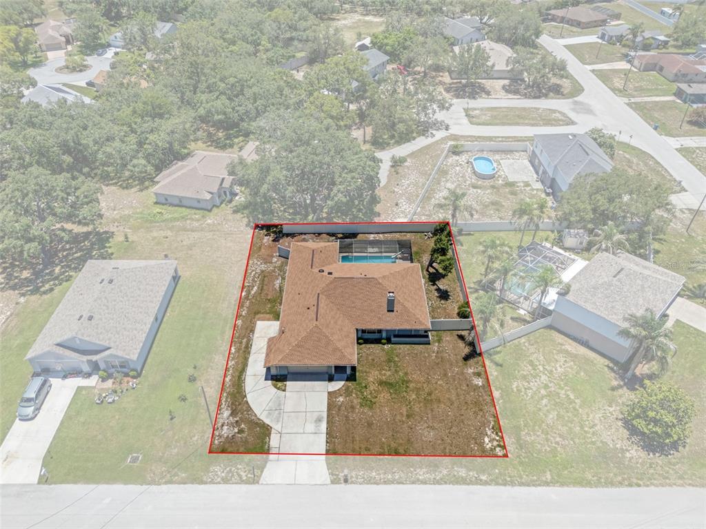 An aerial view shows a single-story house with a pool and fenced yard — 7376 SKYLARK DRIVE, SPRING HILL, FL