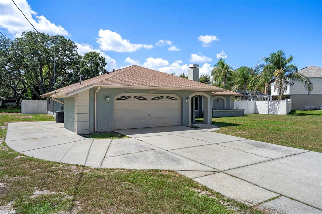 A single-story house with a two-car garage, a concrete driveway, and a fenced yard — 7376 SKYLARK DRIVE, SPRING HILL, FL