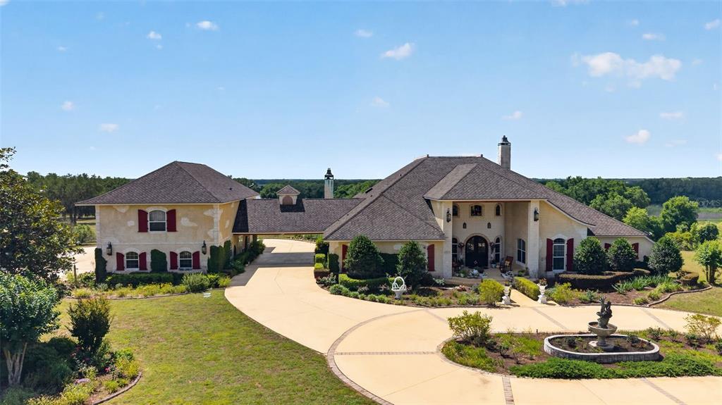 An aerial view shows a large, multi-sectioned house with a circular driveway and fountain — 17269 SE 260TH AVENUE ROAD, UMATILLA, FL