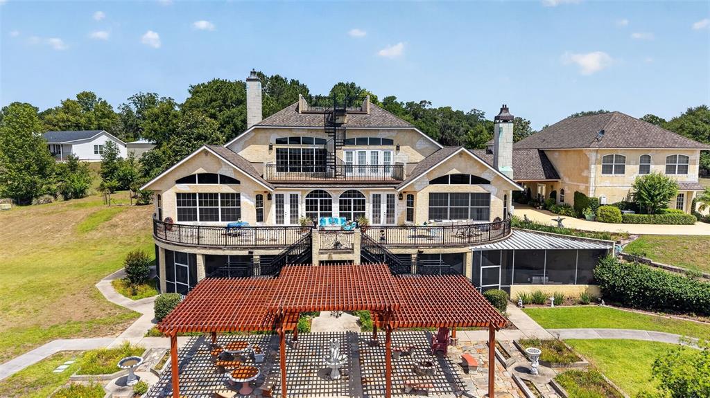 An aerial view of a large multi-story house with a pergola and stone patio — 17269 SE 260TH AVENUE ROAD, UMATILLA, FL