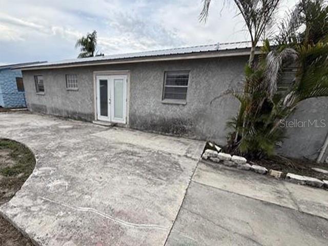 A gray stucco house exterior features a white double door and a concrete patio area — 1129 SW GOLDEN AVENUE, ARCADIA, FL