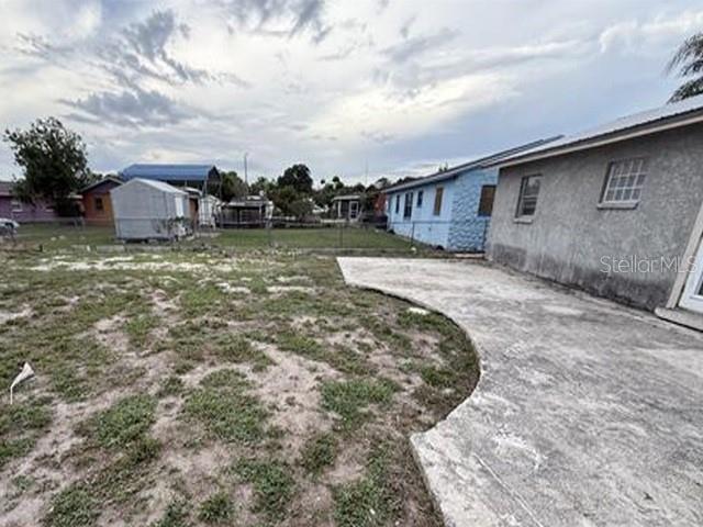 A concrete patio extends from the side of a house into a grassy backyard — 1129 SW GOLDEN AVENUE, ARCADIA, FL
