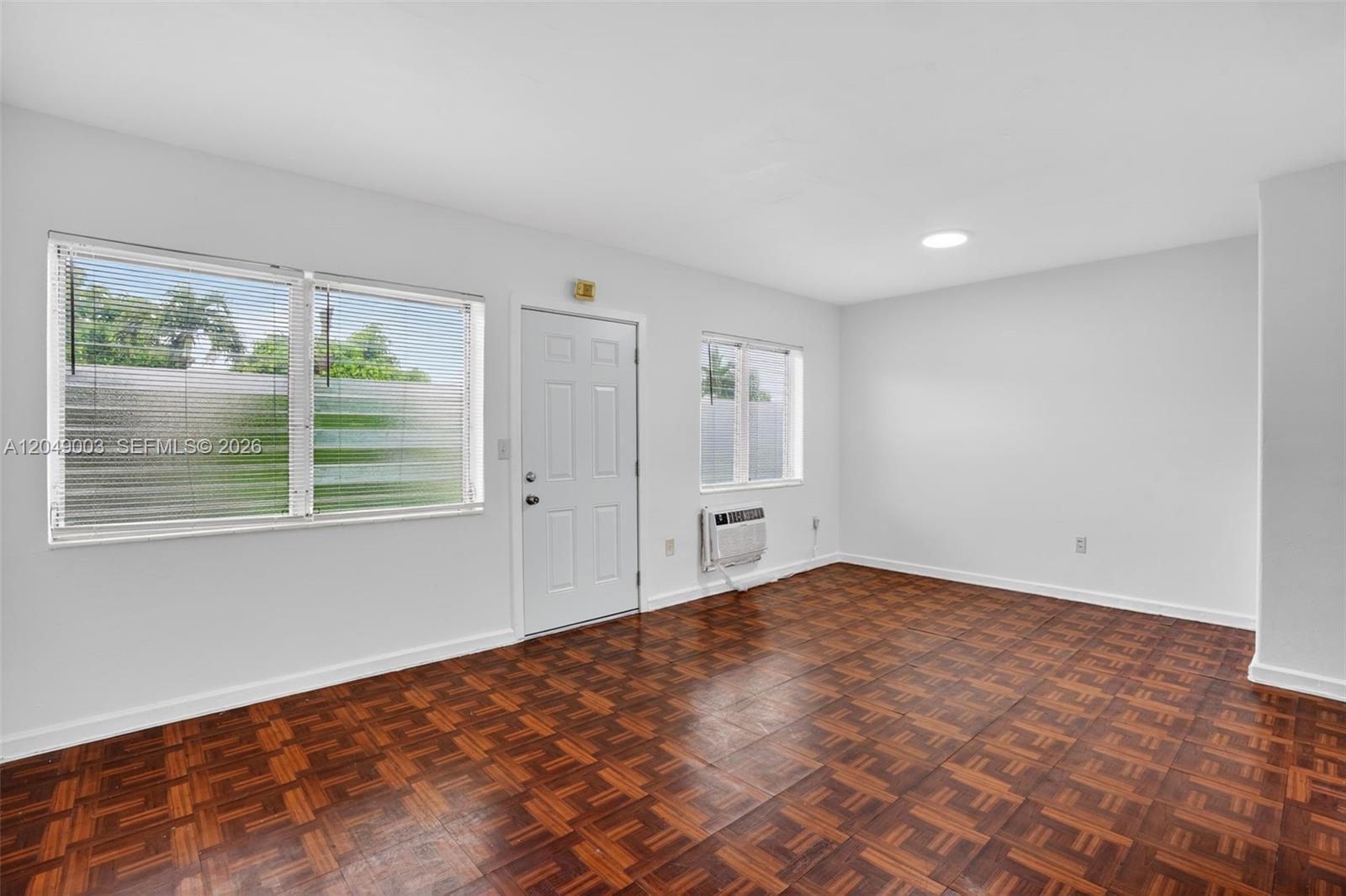 This room features parquet wood flooring, white walls, a white door, and a window air conditioner — 2170 NW Flagler Ter, Miami FL 33125, MIAMI, FL
