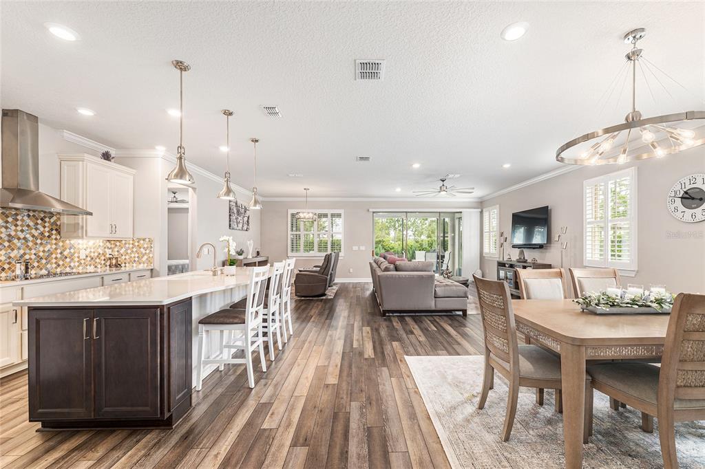 An open-concept kitchen, dining area, and living room feature wood-look flooring and neutral walls — 6259 SW 93RD TERRACE, OCALA, FL