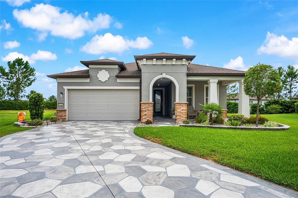 A single-story house with a gray stucco exterior, stone accents, and a patterned concrete driveway — 6259 SW 93RD TERRACE, OCALA, FL