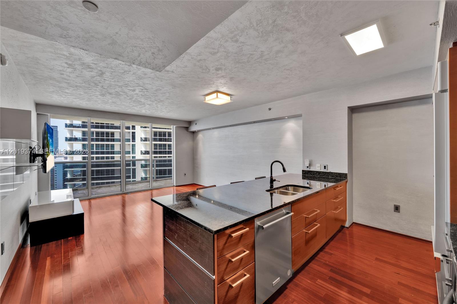 A kitchen island with a dark countertop and wooden cabinets sits on hardwood floors — 1830 S Ocean Dr # 2705, Hallandale Beach FL 33009, HALLANDALE BEACH, FL