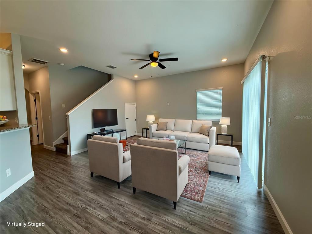 A living room features light-colored furniture, a patterned area rug, and wood-look flooring — 2608 TANOAK TERRACE, WINTER HAVEN, FL