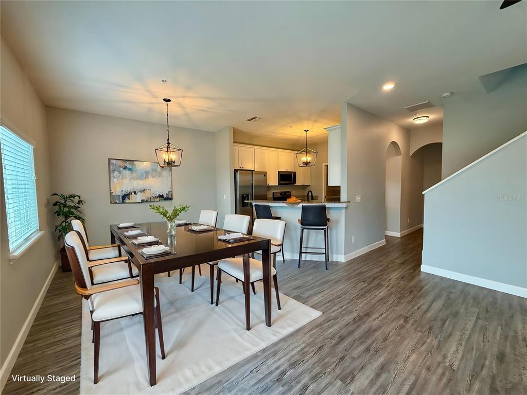A dining area with a dark wood table and chairs sits adjacent to a kitchen — 2608 TANOAK TERRACE, WINTER HAVEN, FL