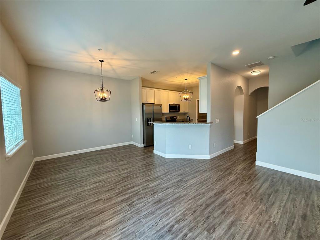 An open-concept dining area and kitchen feature light gray walls, wood-look flooring, and pendant lighting — 2608 TANOAK TERRACE, WINTER HAVEN, FL