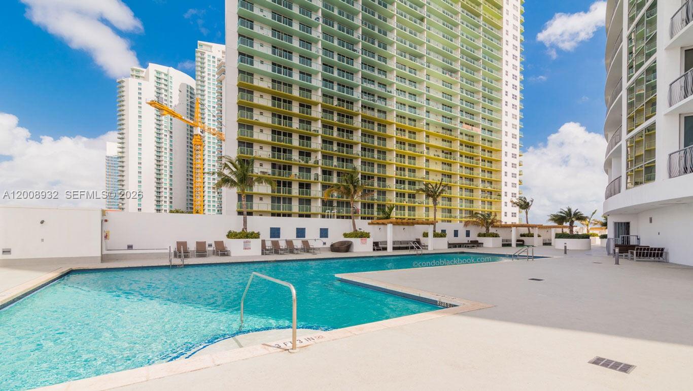 A swimming pool sits on a concrete deck in front of a tall residential building — 1750 N Bayshore Dr # 2514, Miami FL 33132, MIAMI, FL