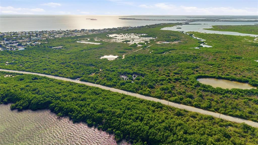 An aerial view shows a road cutting through dense green vegetation and coastal wetlands — NILES ROAD, SUMMERLAND KEY, FL