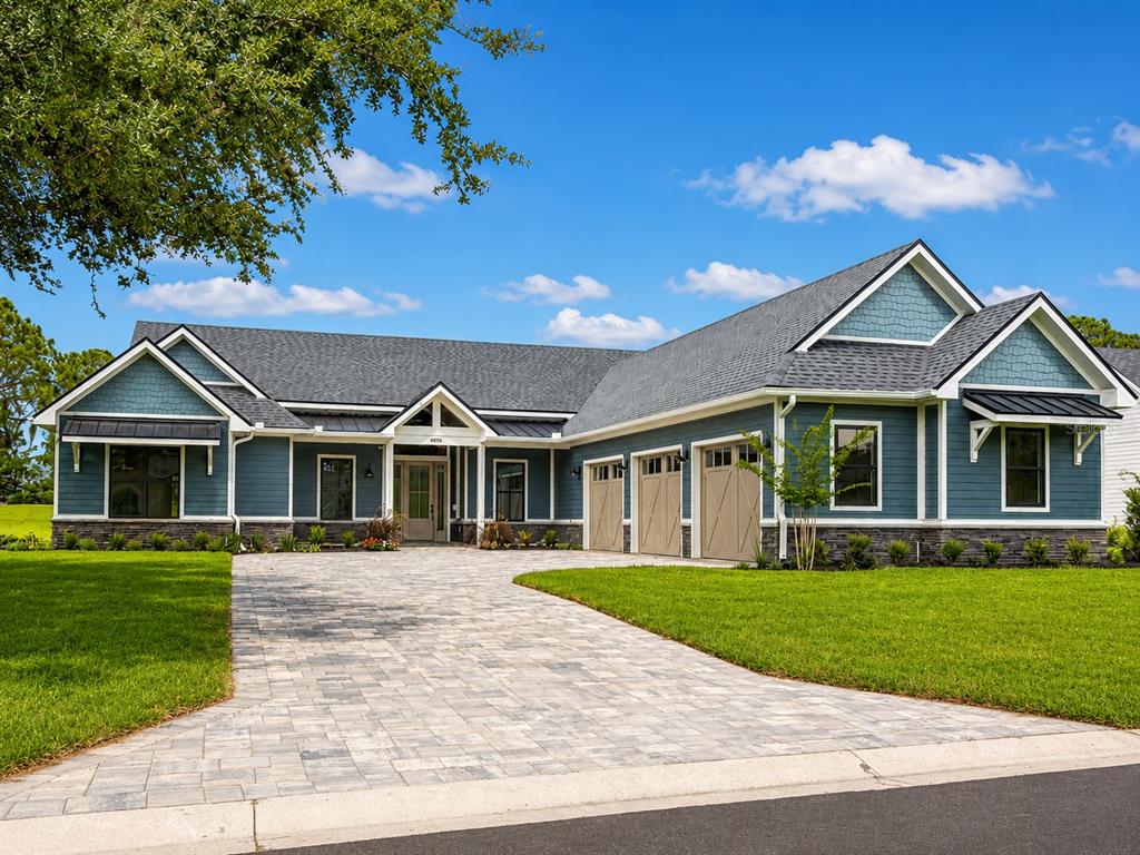 A covered patio features a dining set, an outdoor kitchen with a grill, and blue siding — 4050 PALMA CEIA CIRCLE, WINTER HAVEN, FL