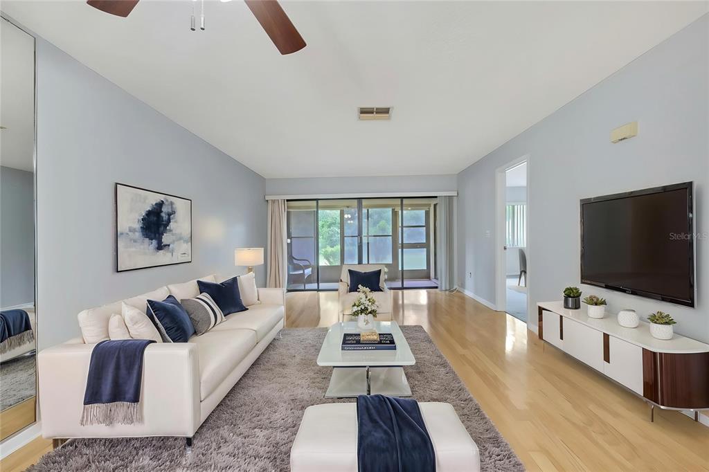 A living room features a white sofa, a glass coffee table, and a wall-mounted television — 63 DOUGLAS STREET UNIT 11, HOMOSASSA, FL