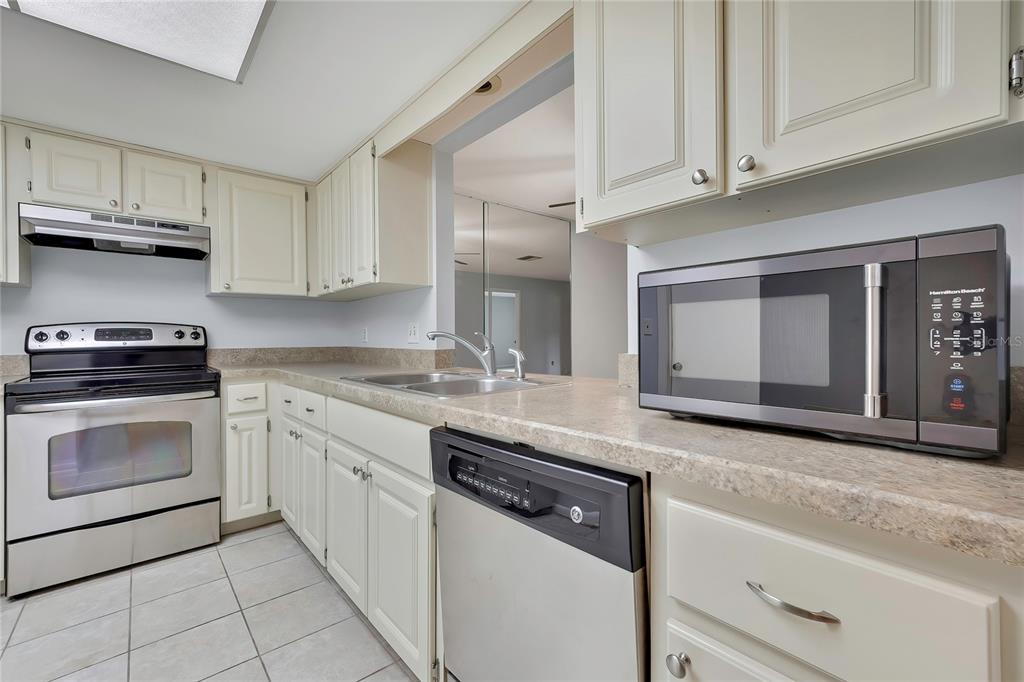 A kitchen features white cabinets, stainless steel appliances, and light-colored laminate countertops — 63 DOUGLAS STREET UNIT 11, HOMOSASSA, FL