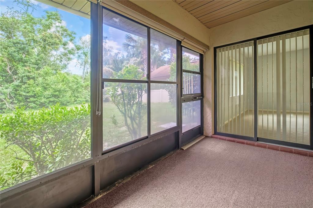 A screened-in porch with a textured floor and sliding glass doors leading to the interior — 63 DOUGLAS STREET UNIT 11, HOMOSASSA, FL
