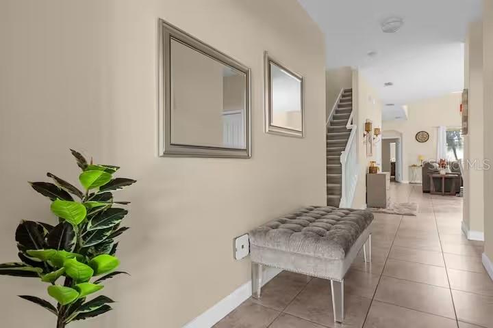 A hallway features a tufted grey bench, two wall mirrors, and a staircase — 8802 BAMBOO PALM COURT, KISSIMMEE, FL