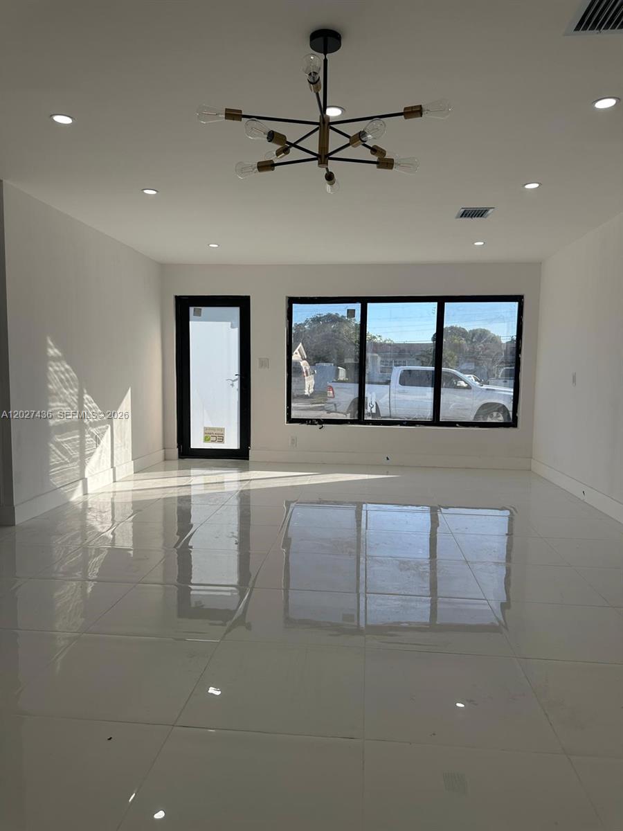 A bright, empty room features white tile floors, recessed lighting, and a modern chandelier — 2041 NW 190th Ter, Miami Gardens FL 33056, MIAMI GARDENS, FL