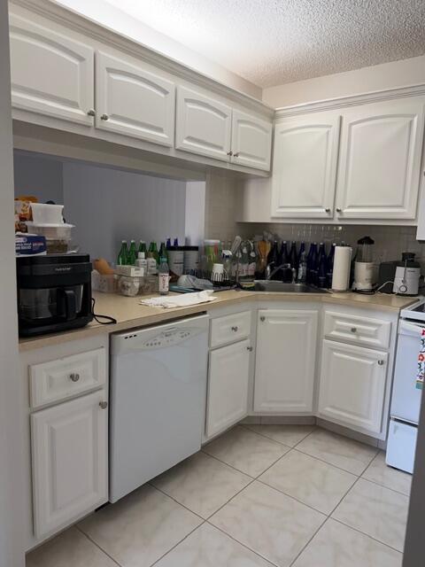 A kitchen features white cabinets, light countertops, tile flooring, and a white dishwasher — 812 Sky Pine Way # D2, FL 33415, FL