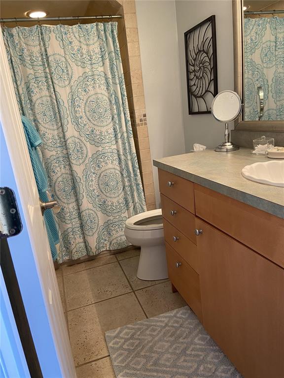 A bathroom features a light wood vanity, a patterned shower curtain, and a tile floor — 4849 SAXON DRIVE UNIT C201, NEW SMYRNA BEACH, FL