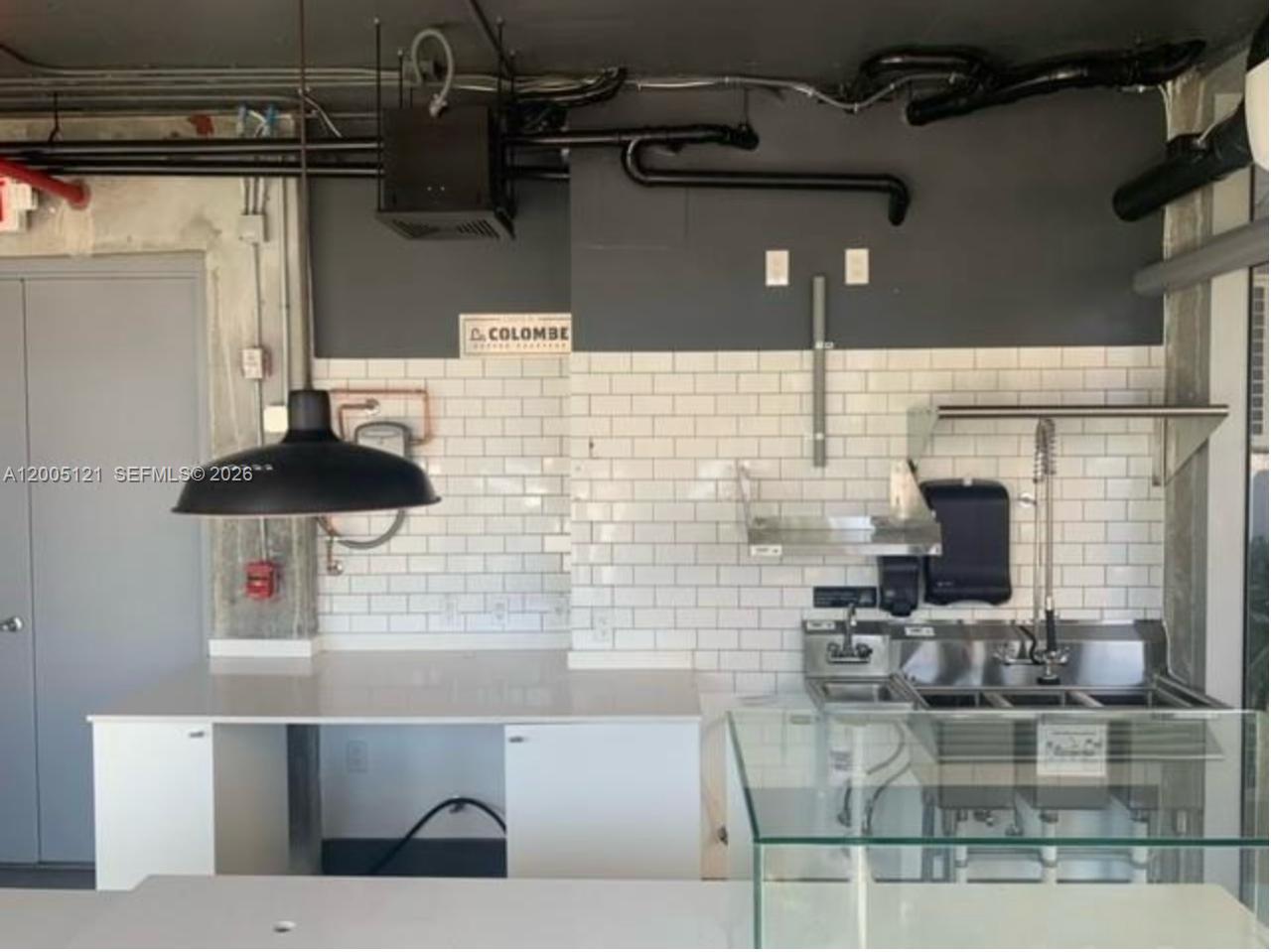 A commercial kitchen area features white subway tile walls, stainless steel sinks, and exposed piping — 538 Meridian Ave, Miami Beach FL 33139, MIAMI BEACH, FL