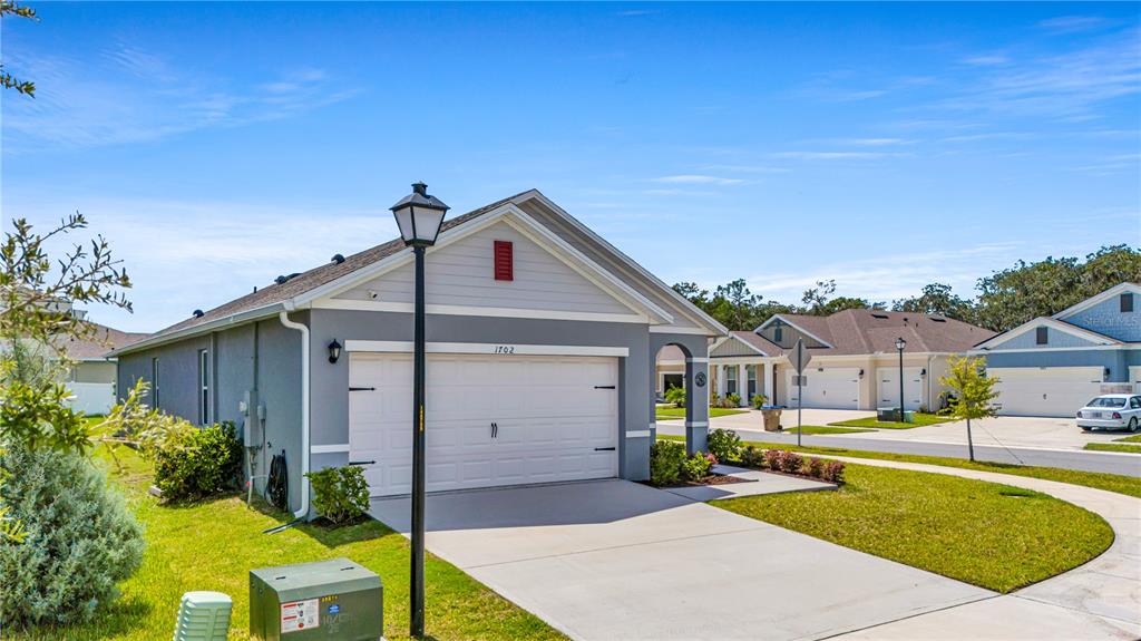 A gray single-story house with a two-car garage and a concrete driveway — 1702 WALNUT CRK DRIVE, KISSIMMEE, FL