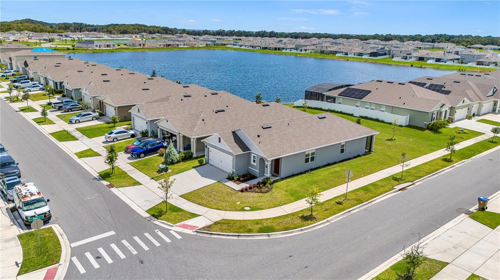 An aerial view shows a suburban neighborhood with houses bordering a large retention pond — 1702 WALNUT CRK DRIVE, KISSIMMEE, FL