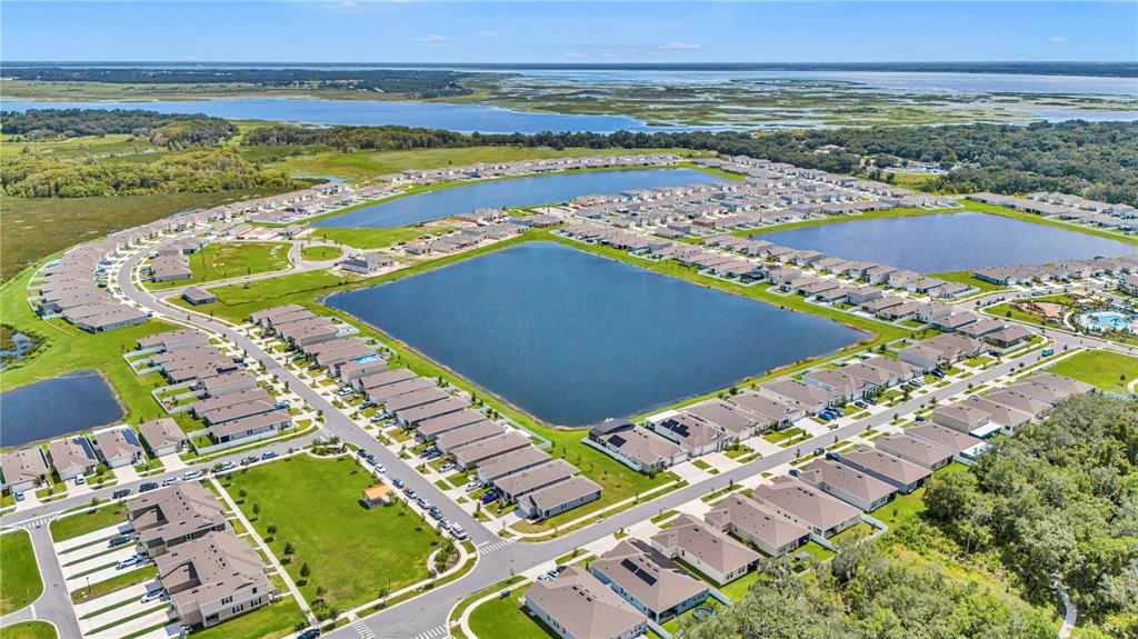 An aerial view shows a suburban neighborhood with houses surrounding several large retention ponds — 1702 WALNUT CRK DRIVE, KISSIMMEE, FL