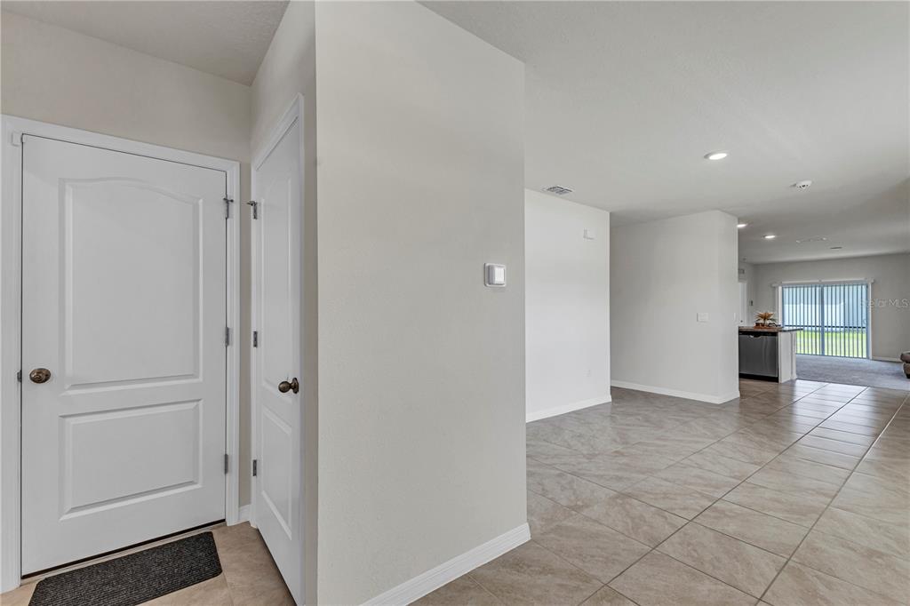 An entryway with tile flooring leads into an open-concept living area with a kitchen — 1702 WALNUT CRK DRIVE, KISSIMMEE, FL