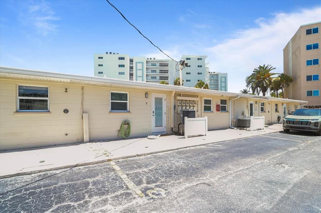 The exterior of a single-story apartment building features beige siding, a parking lot, and a car — 5830 MIDNIGHT PASS ROAD UNIT 3, SARASOTA, FL