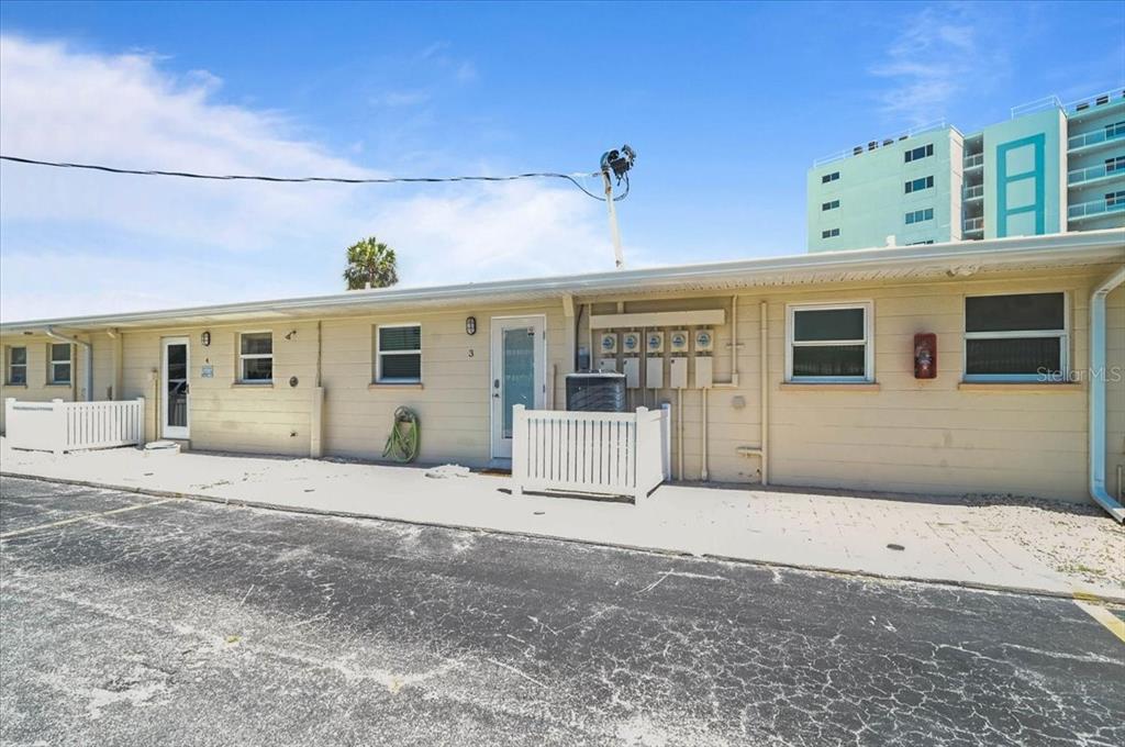 A single-story beige building with multiple doors, windows, and an exterior electrical panel — 5830 MIDNIGHT PASS ROAD UNIT 3, SARASOTA, FL