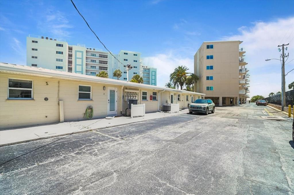 A low-rise building exterior with a parking lot and taller apartment buildings in the background — 5830 MIDNIGHT PASS ROAD UNIT 3, SARASOTA, FL